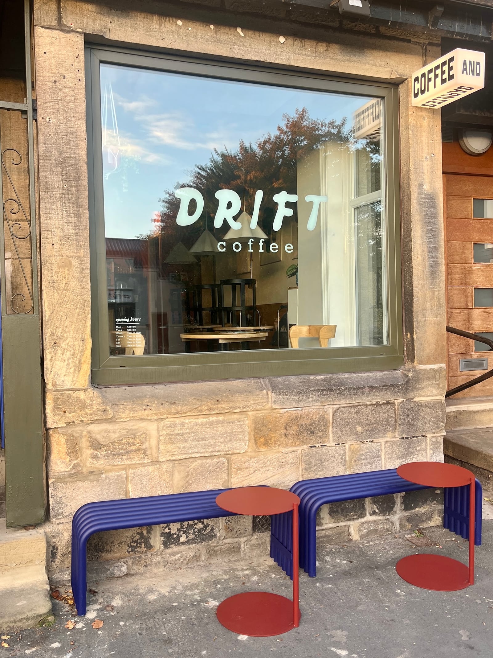 Drift's window lettering above a blue bench and red outdoor tables