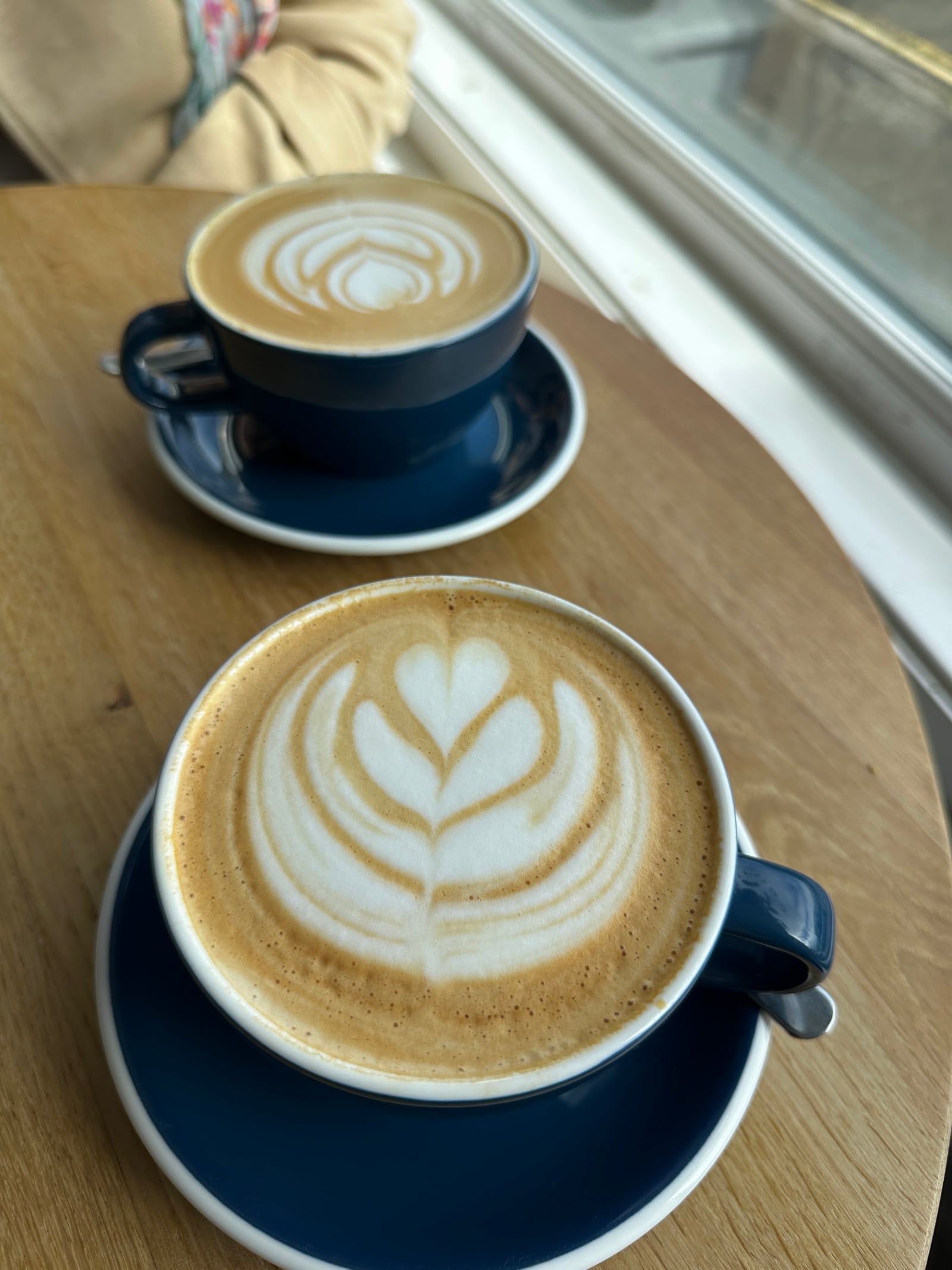 Two beautifully poured coffees on a wooden table at Drift