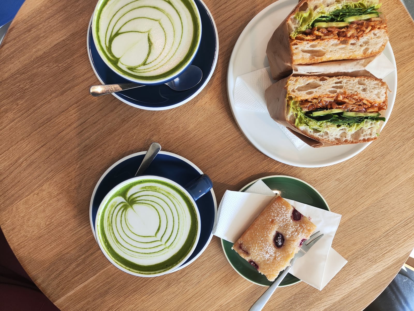 Matcha, a sandwich and a slice of cake together on a Drift café table